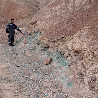 Figure 3. Copper oxides exposed beneath ferruginous (iron rich) soil crust in small creek bed. Note above the exposed mineralization the copper is not visible in the desert soil crust: